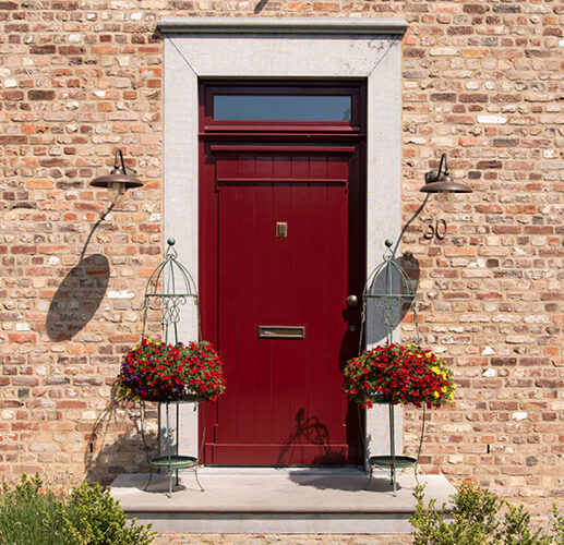 Red front door with 2 plant holders.