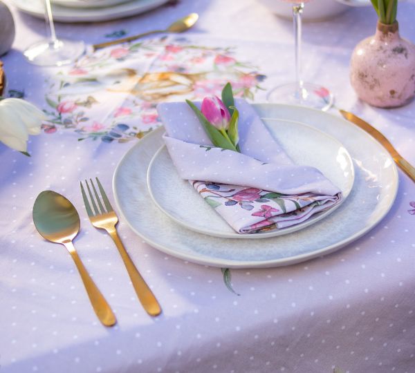 Une assiette sur une table dressée avec une serviette de table colorée et fleurie.