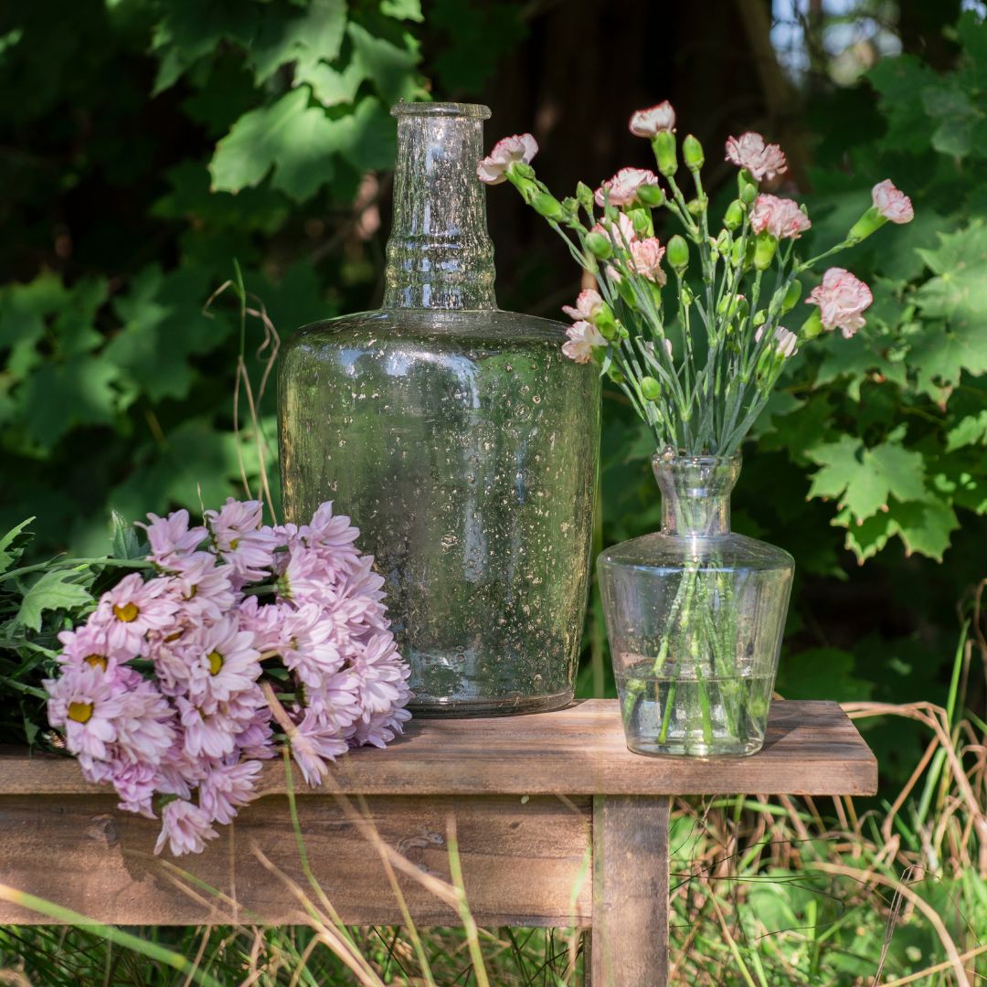 Glasvase und Glasflasche mit rosa Blumen