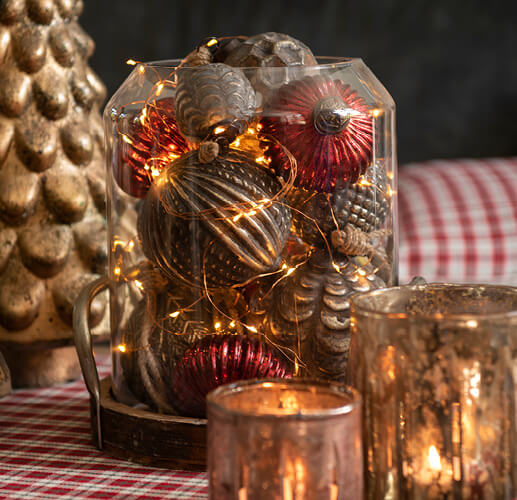 Weihnachtskugeln in einem Glas mit ein paar Kerzen.