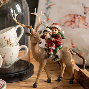 Figurine of 2 children on a reindeer.