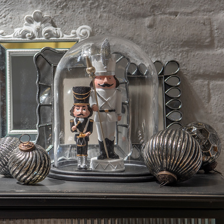 Tendenza natalizia bianco e nero con campana di vetro contenente due schiaccianoci e palline natalizie d'argento