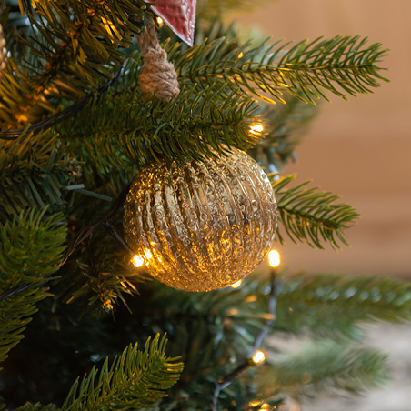 Goldene Christbaumkugel in einem künstlichen Weihnachtsbaum