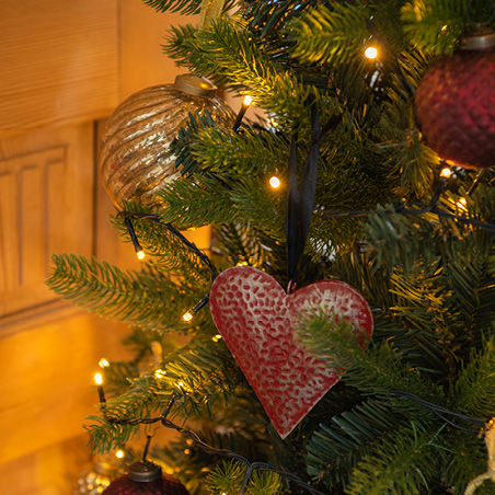 een kerstboom met een gouden kerstbal en een rood hart