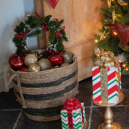 Ghirlanda natalizia con vischio verde e bacche rosse in un cesto pieno di palline natalizie
