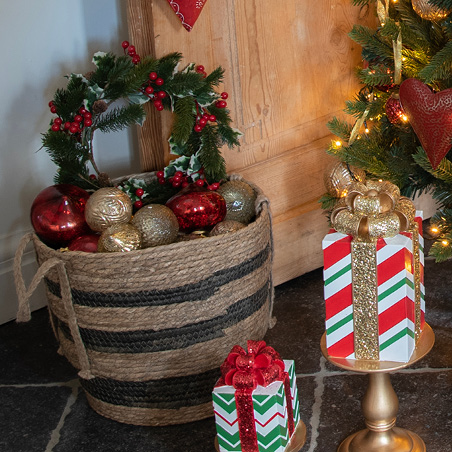 Christmas wreath with green holly and red berries in a basket full of Christmas baubles