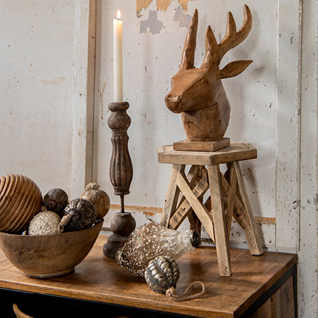 Christmas decoration in natural tones featuring a deer figurine, candle holder, and Christmas baubles