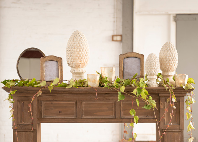 Mantelpiece adorned with sculptures, photo frames, mirrors, and greenery