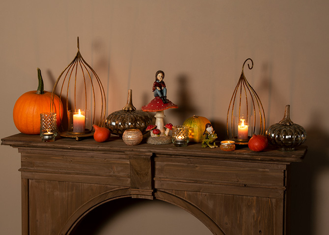Mantelpiece filled with autumn decor, including pumpkins, sculptures, and candleholders