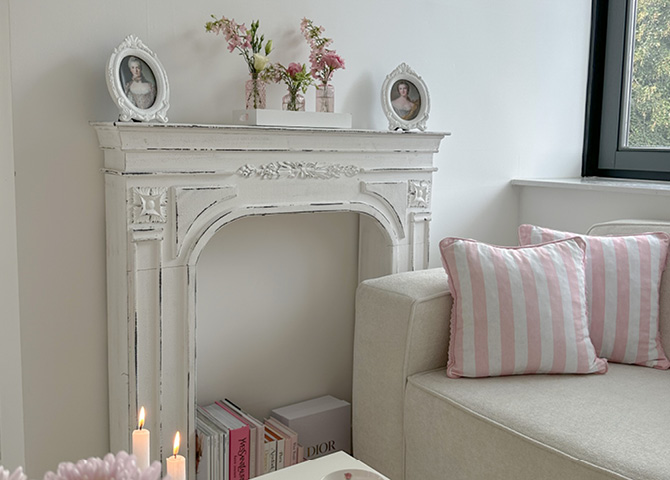 White mantelpiece adorned with photo frames and pink vases