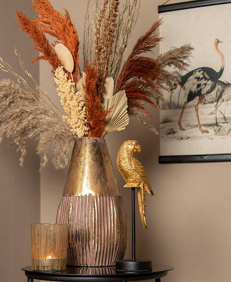Gold-colored vase with dried flowers and a gold-colored parrot figurine
