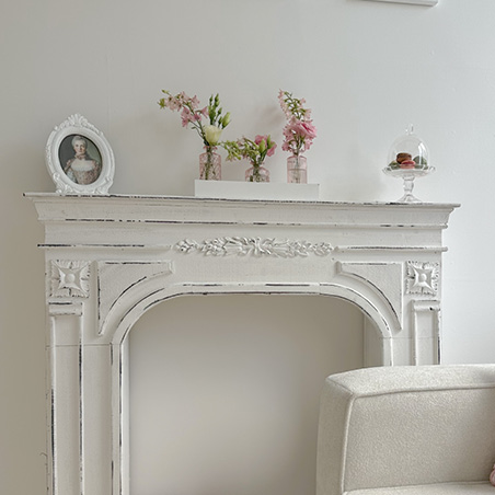 White mantelpiece featuring a photo frame, three small vases, and a cloche
