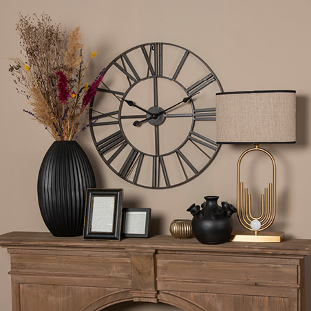 Home decor with a vase of dried flowers, table lamp, photo frames, and a wall clock