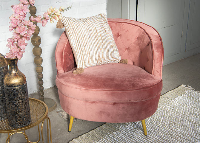 A large pink armchair with a yellow and white decorative pillow in a cozy seating area