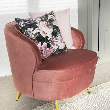 A large pink armchair with two romantic decorative pillows