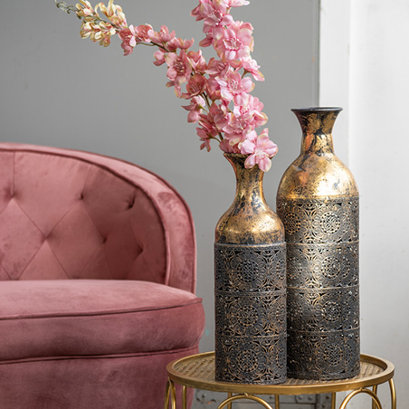 Two gold-colored metal tall vases with pink artificial flowers
