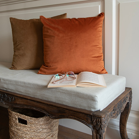 A vintage sofa with brown decorative pillows and an open book