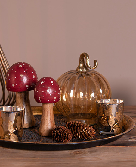 decoratieve schaal gevuld met houten paddenstoelen en glazen pompoenen