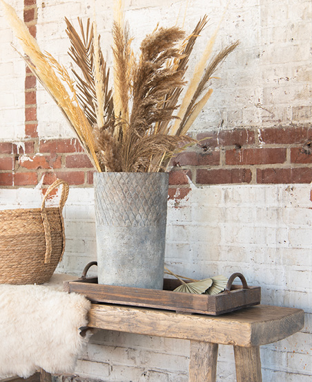 A wicker basket, a tray, and a gray vase with beige dried flowers in a rustic style.