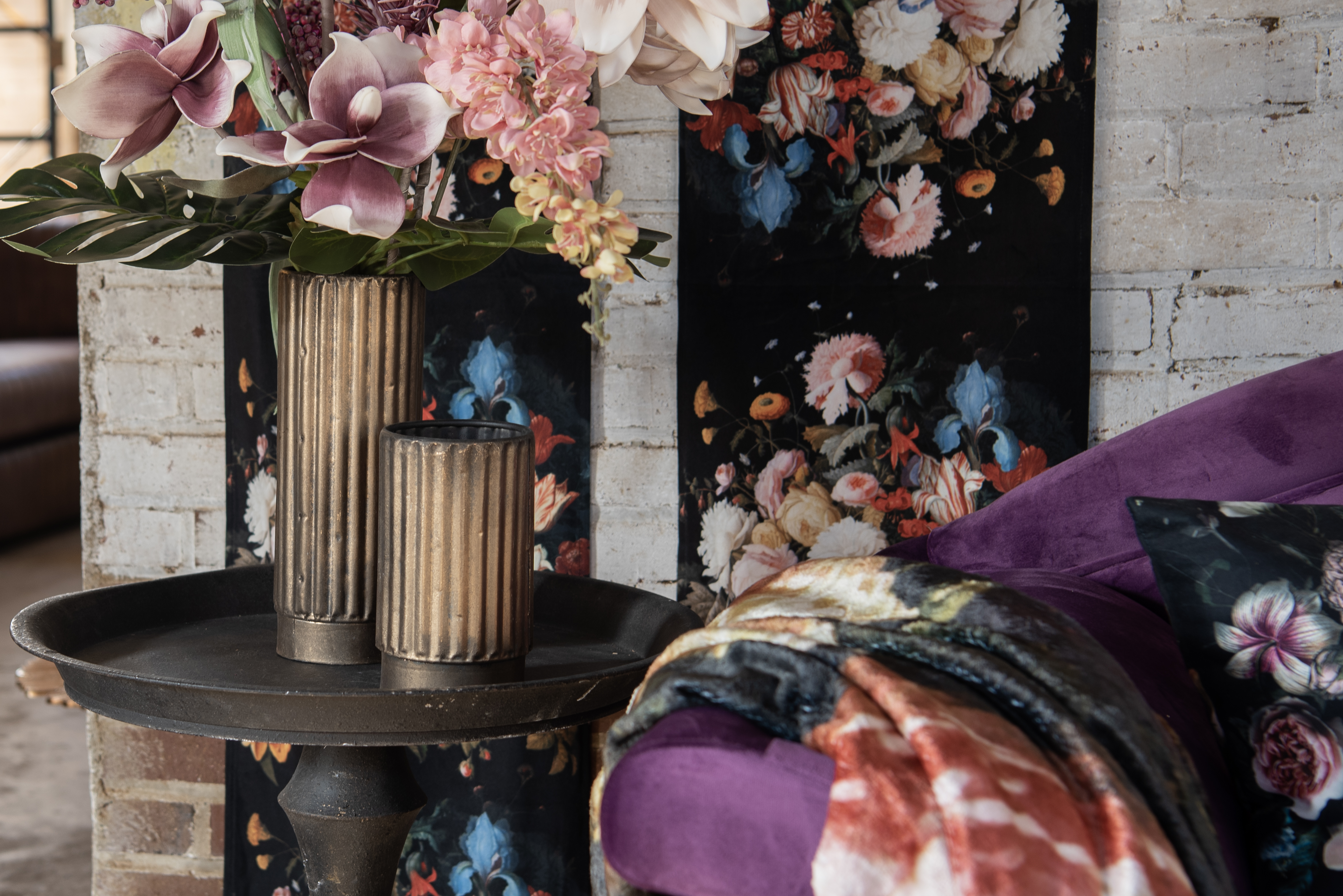 Un divano con un cuscino, un tavolino con vasi per fiori e decorazioni murali.