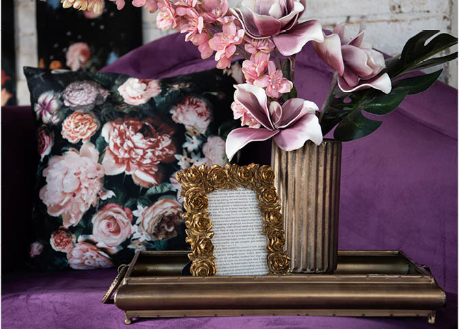 Una cornice per foto, un vaso per fiori, un cuscino e un divano.