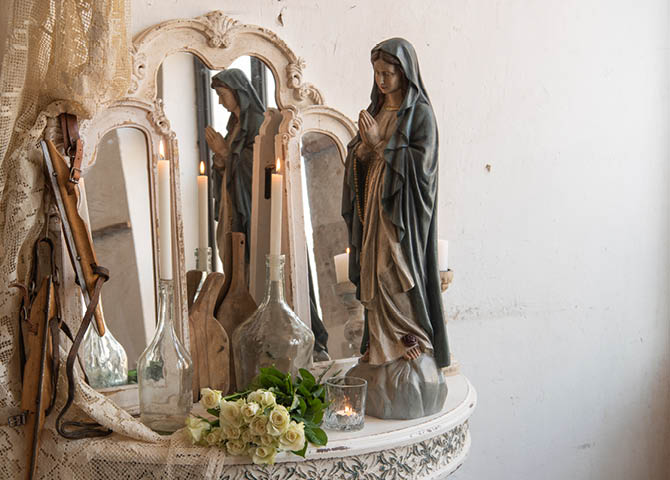 Une table avec des miroirs, une figurine, des vases et des bougies allumées.
