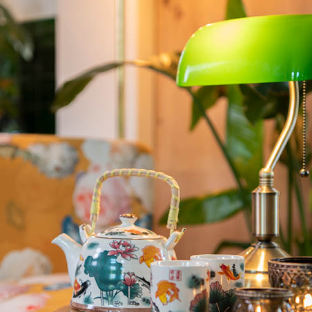 Lampe de banquier verte de style Tiffany et des tasses à thé avec une théière.