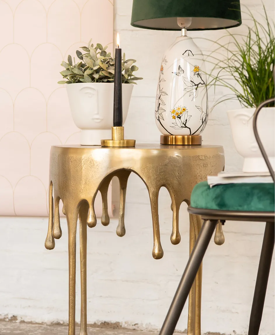 Une table d'appoint moderne, des pots de fleurs, une lampe et un bougeoir.