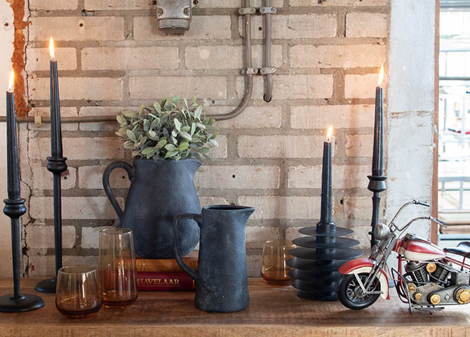 Candle holders with burning candles, pitchers, and glasses in an industrial style.
