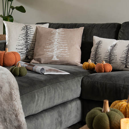 A sofa with cushions and pumpkins.