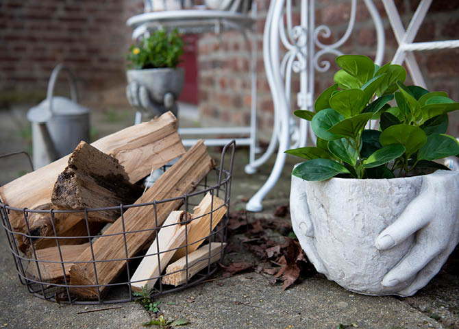 A basket with wood, flowerpots, and a watering can.
