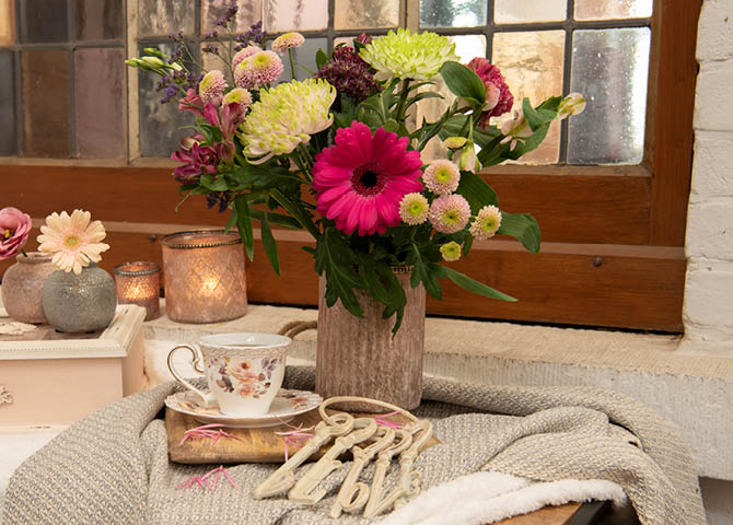 Blumentöpfe, Tasse und Untertasse, Kerzen und eine Teedose.
