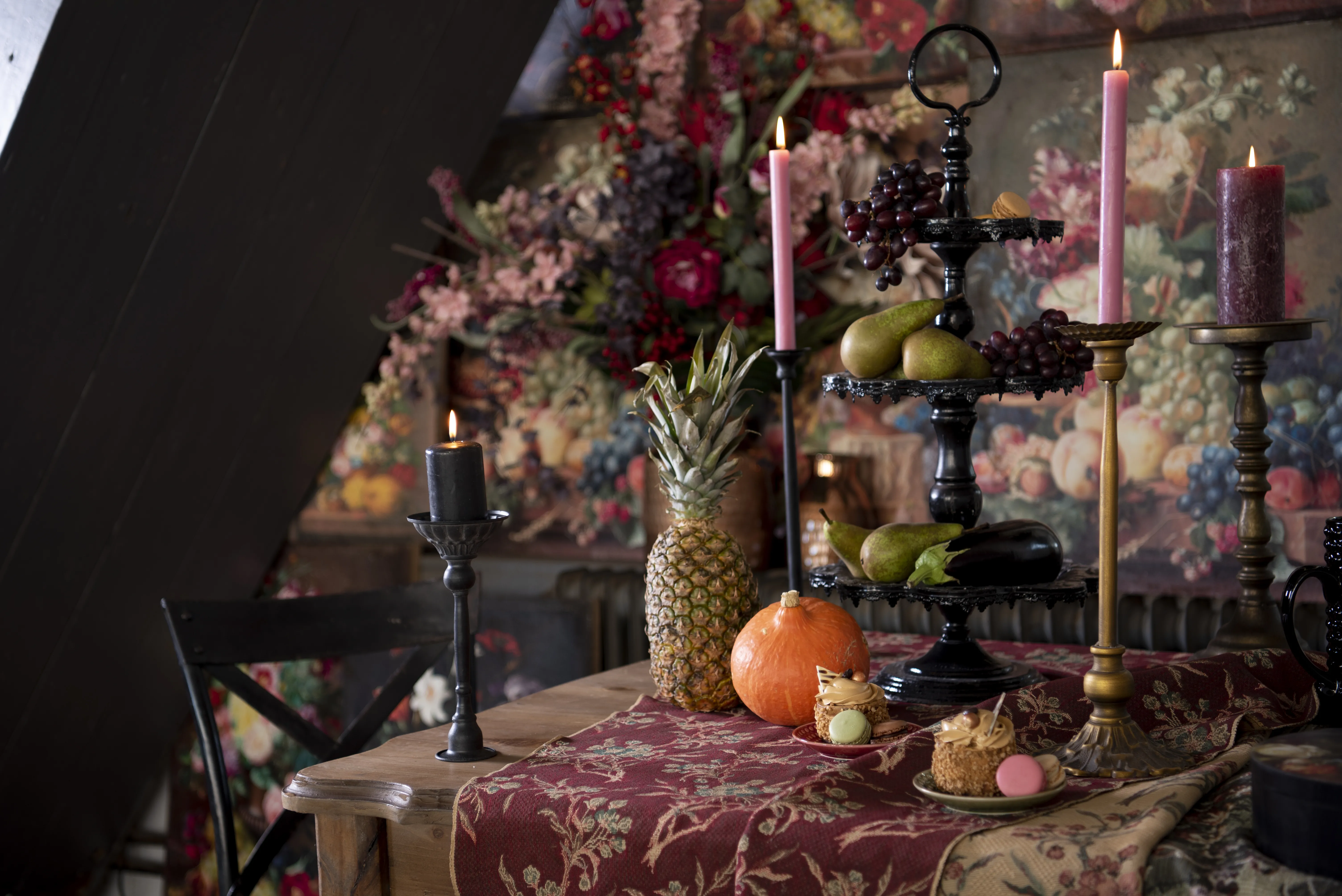 Une table avec une nappe, des bougeoirs, des assiettes et une étagère. À l'arrière-plan, vous pouvez voir une décoration murale.