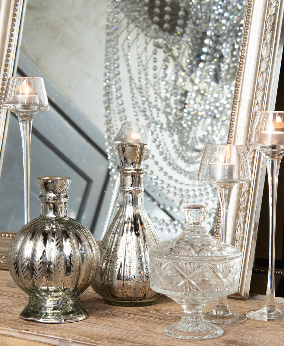 A mirror, candleholders with burning candles, and jewelry boxes.