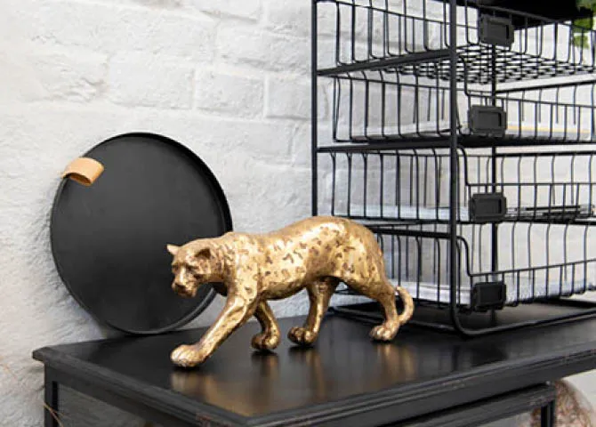 Eine goldene Tigergussfigur, ein Tablett, ein Regal und ein Globus im industriellen Stil.