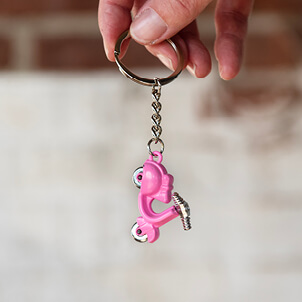 Een sleutelhanger met een kleine roze scooter als hanger.