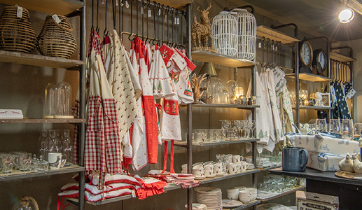 A store display of Christmas textiles with aprons, tea towels, and Christmas tableware