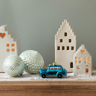 White ceramic decorative houses and a blue car Christmas ornament, along with two light green Christmas ornaments