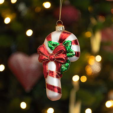 A glass Christmas ornament in the shape of a candy cane with a red ribbon