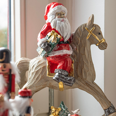 Een houten kerstman met rode kleuren op een bruin paard