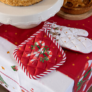 A red pot holder with two candy canes and a white oven mitt with nutcrackers