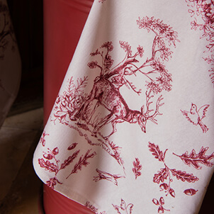 A tea towel with a drawn forest featuring a deer, birds, and autumn leaves