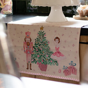 Een kersttafelloper met een kerstboom, notenkraker, ballerina en cadeautjes