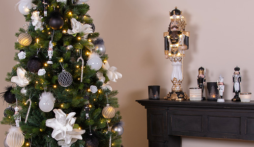 La tendance de Noël en noir et blanc avec un sapin de Noël rempli de décorations et de boules de Noël noires et blanches, ainsi qu'une cheminée noire avec des casse-noisettes noirs et blancs et des porte-bougies noirs et blancs
