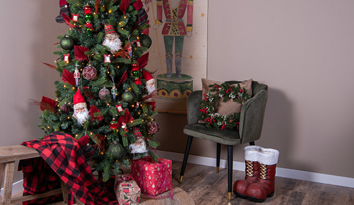 La traditionnelle décoration de Noël en rouge et vert avec un sapin de Noël rempli de boules de Noël et d'ornements rouges et verts, ainsi qu'une chaise verte avec un coussin décoratif et une couronne de Noël avec un plaid à carreaux