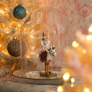 A pink nutcracker in a glass cloche