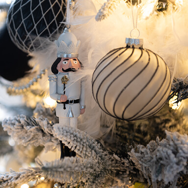 Un casse-noisette blanc dans le sapin de Noël avec une boule de Noël noir et blanc