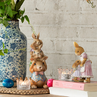 Fröhliche Osterfiguren mit Glas-Teelichthaltern und einer ländlichen blauen Vase