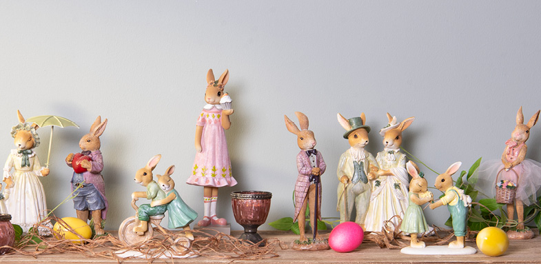 A wall shelf with various colorful rabbit statues with colored eggs