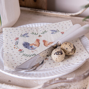 A white breakfast plate with a chicken paper napkin, a knife, and quail eggs
